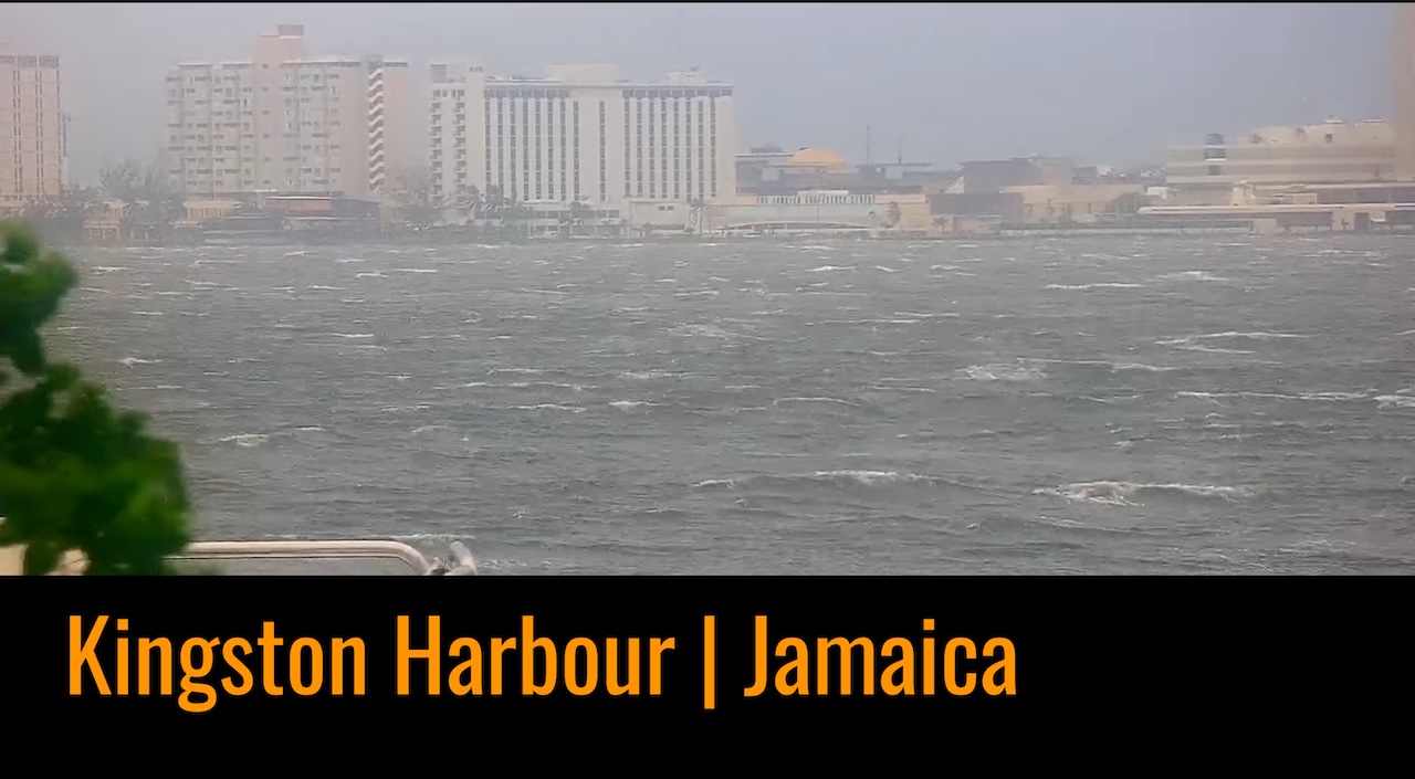 Live PTZ view of Kingston Harbour in Jamaica, rotating between preset angles to show ships, waterfront and current weather conditions.
