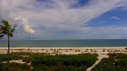 PTZ live beach view from a condo on Sanibel Island, Florida, showing waves, ocean boats, and people on the sand.