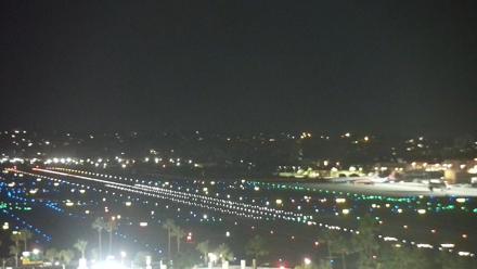 Airport runway and San Diego Bay visible beyond, with several aircraft and waterfront in view