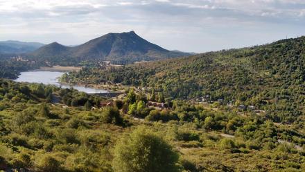 A serene lake view beneath a partly cloudy sky, framed by distant hills and reflective water