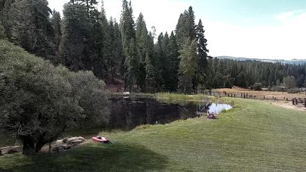 Rustic saloon deck and surrounding ranch grounds under soft daylight, with western atmosphere and distant pastures