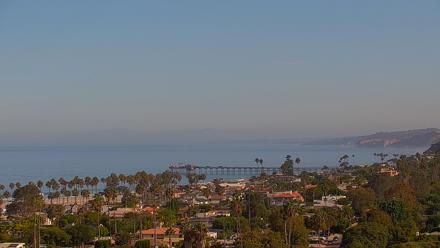 Overlook view of La Jolla Shores Beach in San Diego showing ocean waves, Scripps Pier and coastal bluff at sunset.