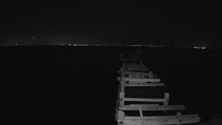 Fixed view down the Rod & Reel Pier in Anna Maria Florida showing the sign post and the pilings of the former pier over clear Gulf water.