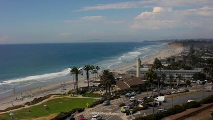 Expansive view from a bluff overlooking Del Mar Beach, surf rolling against the shore under soft light