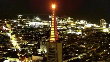 Northwest view of the Golden Gate Bridge over San Francisco Bay with city rooftops and boats seen from a high rise camera.