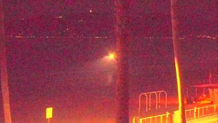PTZ surf cam roves over El Porto shoreline, surfers and rolling waves by lifeguard towers in Manhattan Beach, California.